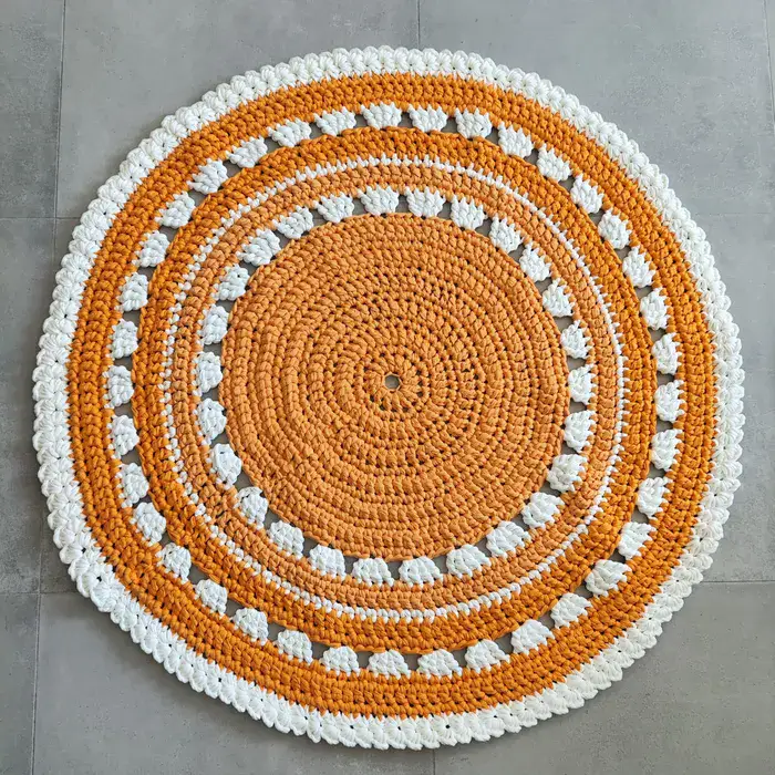 שטיח עגול בצבע כתום עם עיטורים לבנים